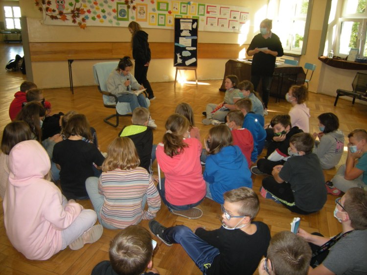 Dzieci z klasy pierwszej drugiej i trzeciej słuchają bajek czytanych przez starsze koleżanki i kolegów