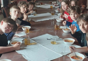 Uczniowie na stołówce podczas obiadu, zajadają się pyszną zupą pomidorową.
