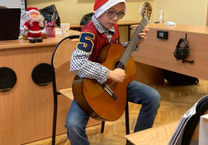 Uczeń klasy IV Maciej Grochulski gra na gitarze kolędy