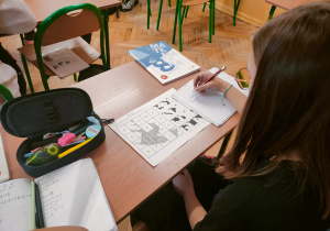 Uczennica zmagająca się z zadaniami matematycznymi z nutą halloweenowej tajemnicy.