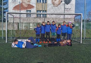 Uczniowie przy bramce do piłki nożnej ubrani na niebiesko pozują do zdjęcia. Uczestniczyli w zawodach Mistrzoswa Łodzi w piłce nożnej dla chłopców - 23.października 2025 r.