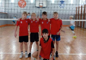 Uczniowie przy siatce do piłki siatkowej ubrani na czerwono pozują do zdjęcia. Uczestniczyli w zawodach Igrzyska Dzieci w Łodzi w piłce siatkowej dla chłopców - Szkoła Podstawowa nr 56 w Łodzi24-25 listopada 2025 r.