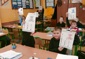uczniowie klasy 4 trzymający odkodowane karty pracy z misiami