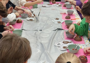 Uczniowie klasy trzeciej z zaangażowaniem wykonują czekoladowe bombki