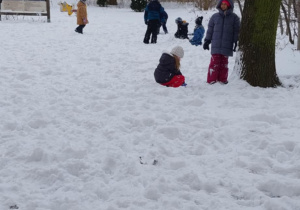 Dzieci podczas śnieżnych zabaw - lepią bałwanki, siedzą na śniegu