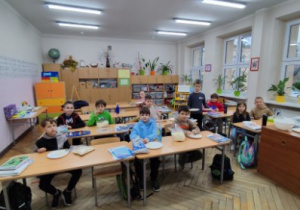 Uczniowie oglądają film na tablicy multimedialnej i zajadają się popcornem