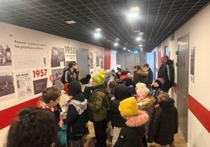 Stadion ŁKS, jesteśmy w korytarzu historii drużyny ŁKS. Uczestnicy oglądają stare zdjęcia, czytają historie klubu, pan również przybliża historię tego klubu