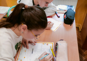 Uczennice klasy 7 z zaangażowaniem rozwiązują zadania w układzie współrzędnych podczas Matematycznych Walentynek.