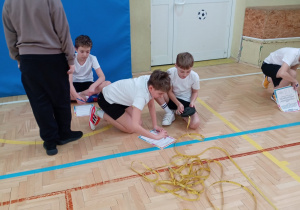 Maksymalne skupienie na detalu – uczennice precyzyjnie mierzą punkt styku linii białej i żółtej, dbając o każdy centymetr.