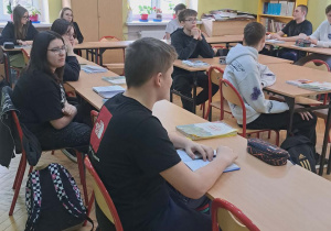 Uczniowie klasy ósmej siedzą w ławkach i wysłuchują ofert edukacyjnej jednej ze szkół ponadpodstawowych