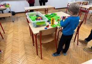 Przed przyszłym uczniem na stole leżą różne kolorowe klocki. Dziecko układa z nich różne kompozycje.