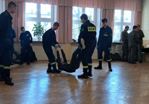 Uczniowie szkoły ponadpodstawowej przenoszą ucznia za ręce i nogi.