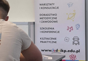 Uczeń przed banerem edukacyjnym.