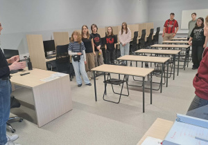Uczniowie klasy VIII wraz z wychowawcą w pięknej nowoczesnej sali komputerowej słuchają oferty nauczyciela ze Szkoły Hotelarsko - Turystycznej.