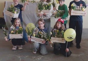 Uczniowie klasy III pozują na tle ściany ze swoimi pracami