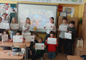 Uczniowie klasy 3 dumnie prezentują swoje autorskie broszurki z zadaniami matematycznymi, które pozwoliły im poznać tajemnice liczby Pi podczas wspólnych obchodów jej święta.