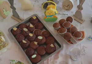 Zdjęcie przyszykowane stołu wielkanocnego. Na stole różne smakołyki babeczki, kolorowe kanapeczki, zajączki.