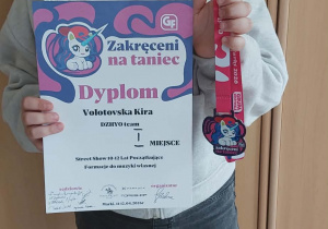 Uczennica klasy III pozuje do zdjęcia prezentując dyplom i medal za zajęcie I miejsca w konkursie tanecznym ,,Zakręceni na taniec"
