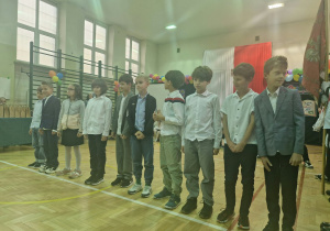 Sala gimnastyczna, na zdjęciu klasa trzecia wykonuje piosenkę z okazji Dnia Edukacji Narodowej