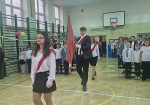 Sala gimnastyczna,wejście Pocztu Sztandarowego, w tle społeczność szkolna.