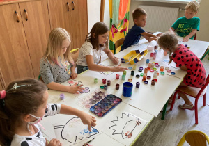Dzieci kropkują farbami obrazki.